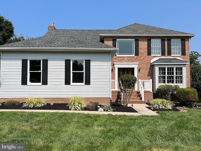 view of front of property featuring a front lawn and a shingled roof