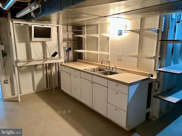 kitchen with white cabinetry, light countertops, and a sink