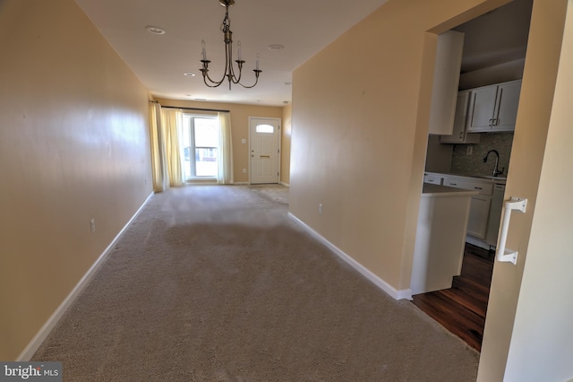 hallway featuring carpet flooring, a sink, and baseboards