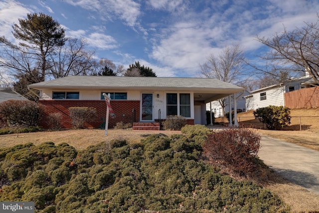 single story home with fence, an attached carport, concrete driveway, and brick siding