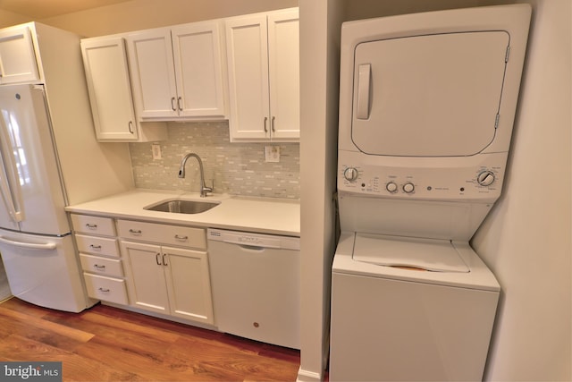 washroom with laundry area, stacked washer and clothes dryer, a sink, and wood finished floors