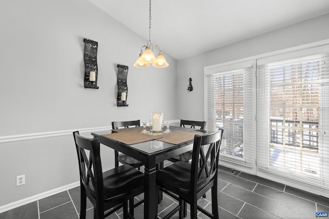 dining space featuring a notable chandelier, vaulted ceiling, dark tile patterned floors, and baseboards