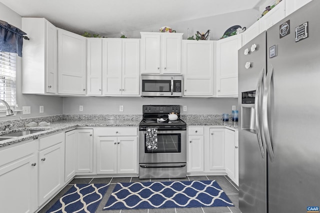 kitchen with appliances with stainless steel finishes, a sink, light stone counters, and white cabinets