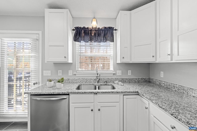 kitchen featuring dishwasher, a sink, and white cabinets