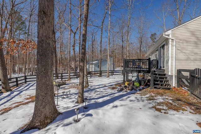 yard covered in snow with fence and a deck