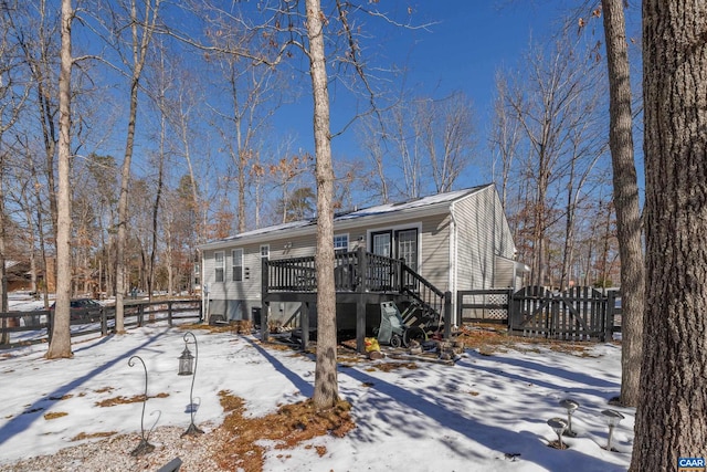 snow covered rear of property featuring stairs, fence, and a wooden deck