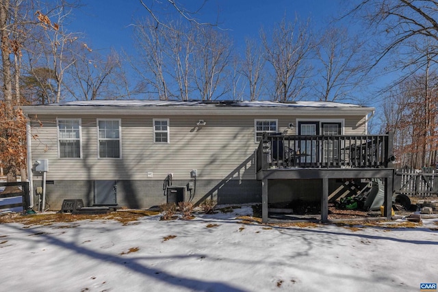 snow covered property with central air condition unit, stairway, and a deck