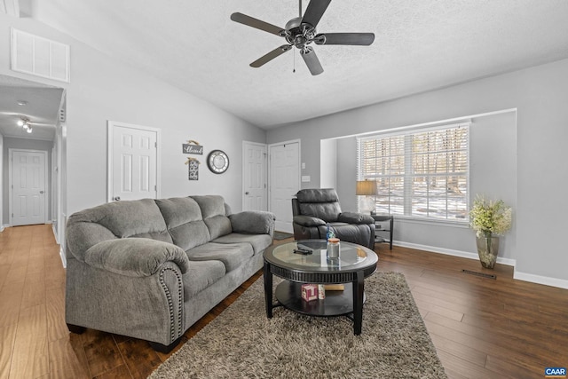 living area with lofted ceiling, visible vents, dark wood-type flooring, a textured ceiling, and baseboards