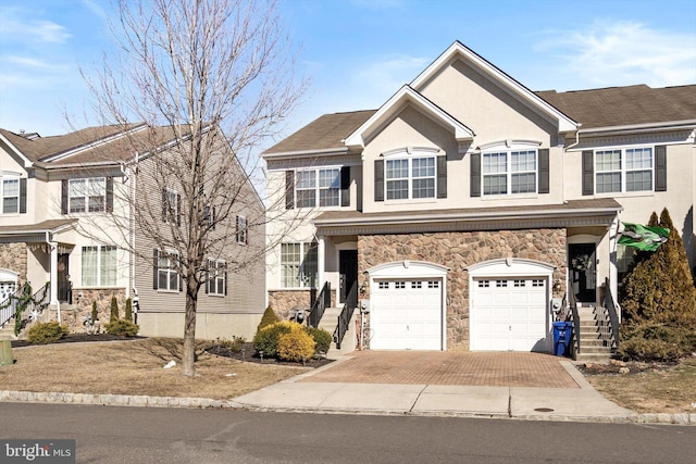 view of front of property with a garage, stone siding, stairway, and decorative driveway