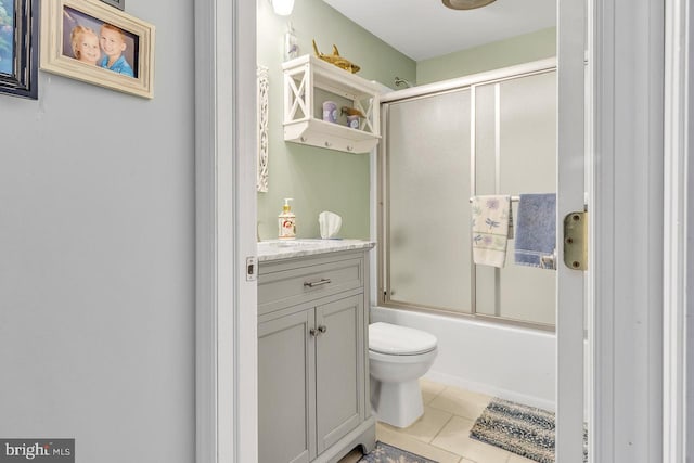 bathroom featuring enclosed tub / shower combo, toilet, vanity, and tile patterned floors