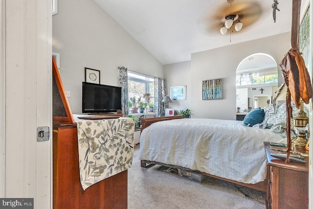 bedroom with high vaulted ceiling, arched walkways, carpet flooring, and a ceiling fan