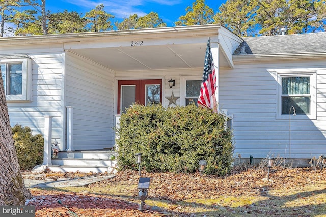 view of exterior entry with roof with shingles, french doors, and crawl space