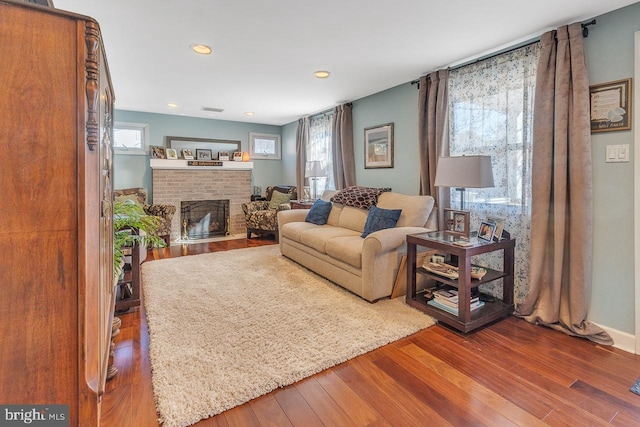 living room featuring a brick fireplace, wood finished floors, visible vents, and recessed lighting