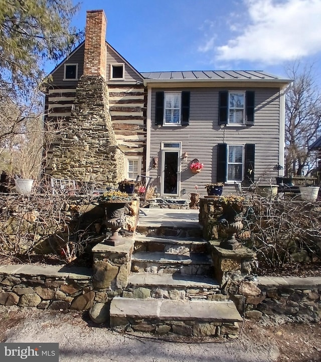 view of front facade featuring metal roof, a standing seam roof, and a chimney