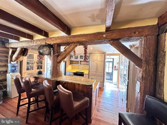 bar with light wood-style flooring and beamed ceiling