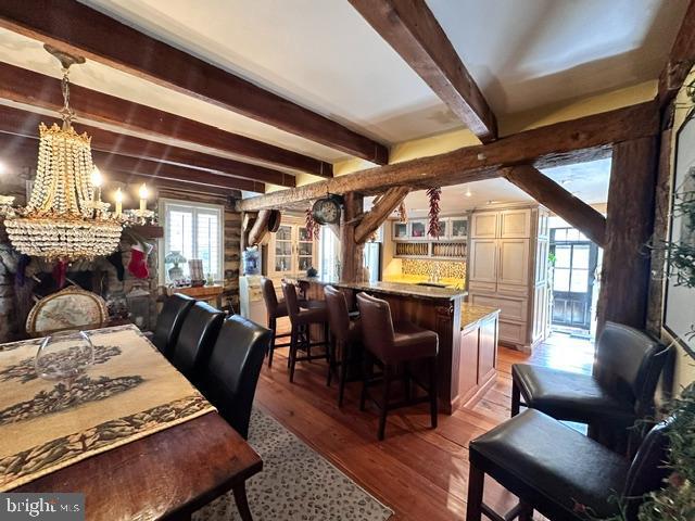 dining area featuring a chandelier, beamed ceiling, and wood finished floors