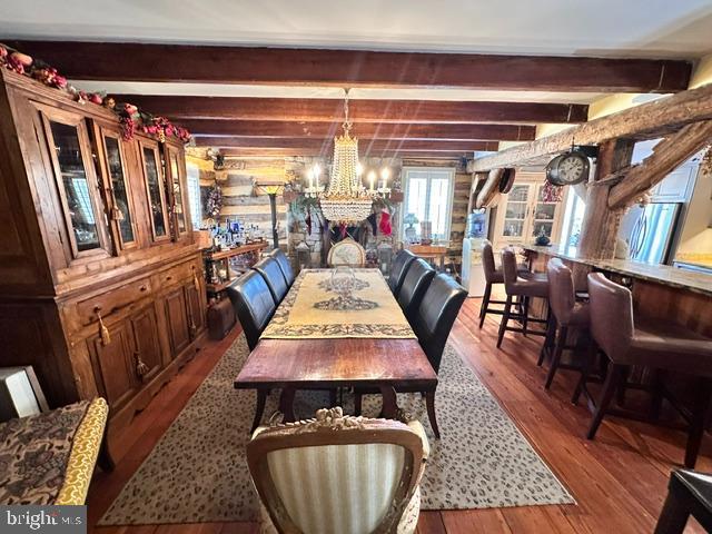 dining room with an inviting chandelier, beam ceiling, and hardwood / wood-style flooring