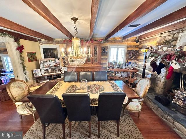 dining area featuring a chandelier, beamed ceiling, and wood finished floors