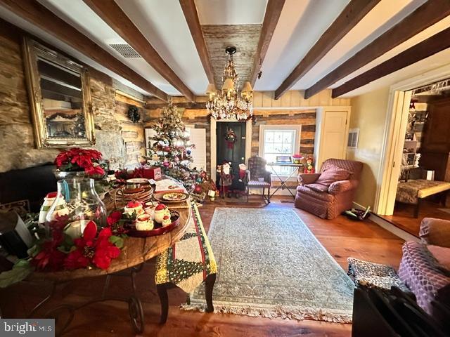 dining room featuring visible vents, a notable chandelier, beamed ceiling, and wood finished floors