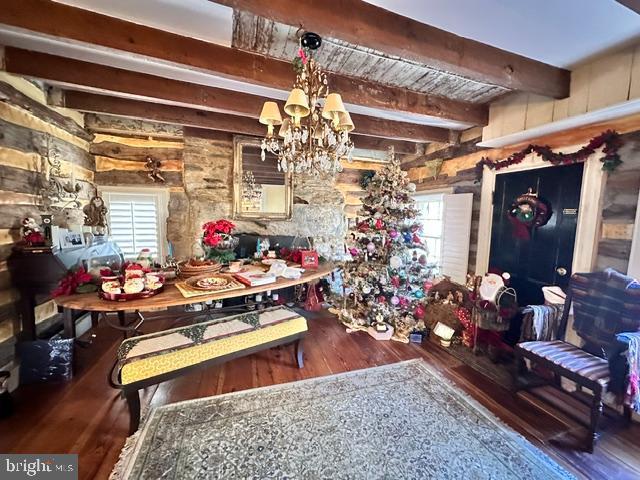 dining area with beam ceiling, an inviting chandelier, and wood finished floors