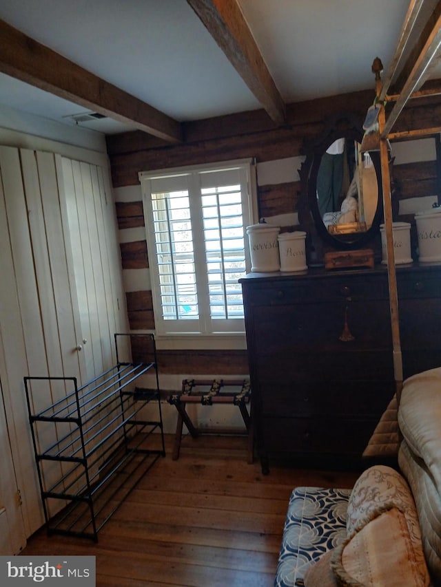 bedroom featuring wood walls, visible vents, hardwood / wood-style floors, and beamed ceiling