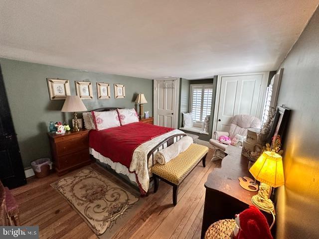 bedroom with baseboard heating and hardwood / wood-style floors