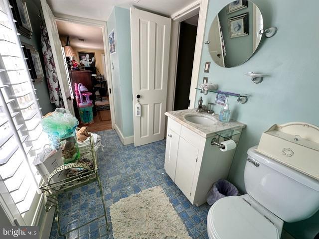 half bathroom featuring baseboards, vanity, and toilet