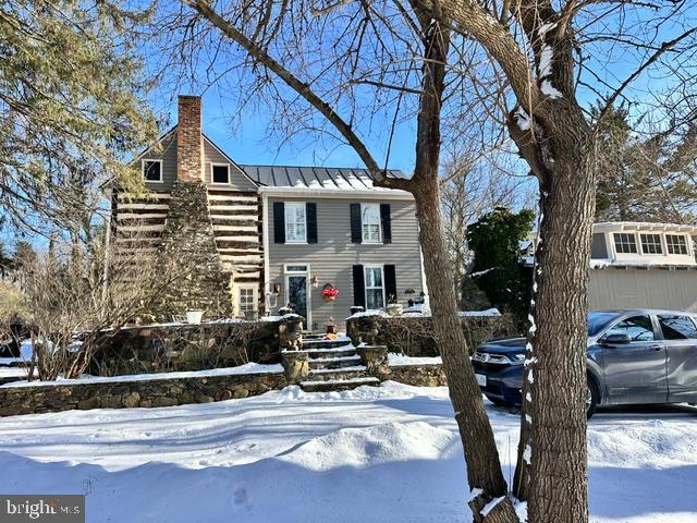 view of front of property featuring metal roof, a standing seam roof, and a chimney