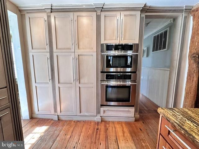 kitchen with double oven, stone countertops, visible vents, and light wood-style flooring