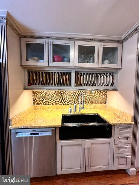 bar featuring dark wood finished floors, backsplash, a sink, wet bar, and dishwasher