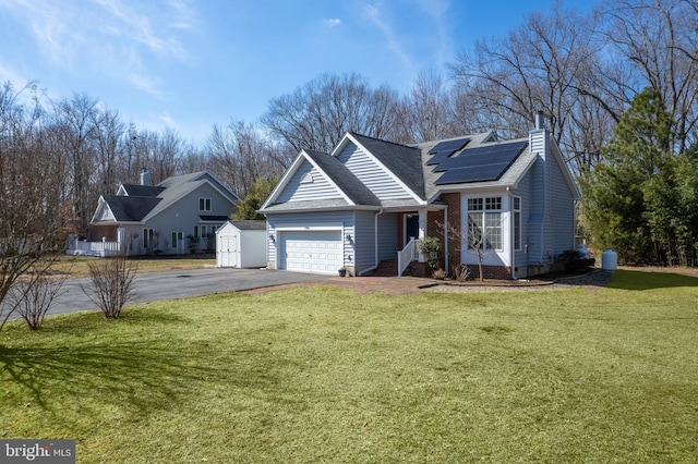 ranch-style home featuring driveway, solar panels, a chimney, an attached garage, and a front yard