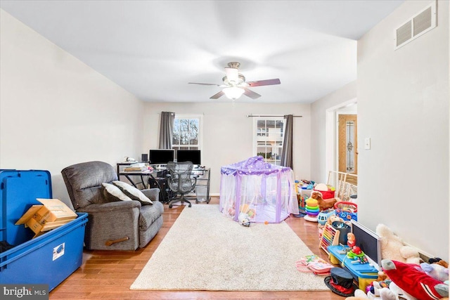 game room with light wood-style floors, visible vents, and a ceiling fan