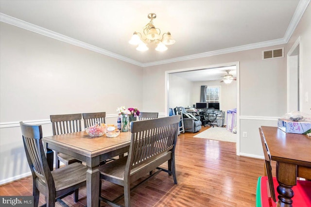 dining space featuring crown molding, wood finished floors, visible vents, and baseboards