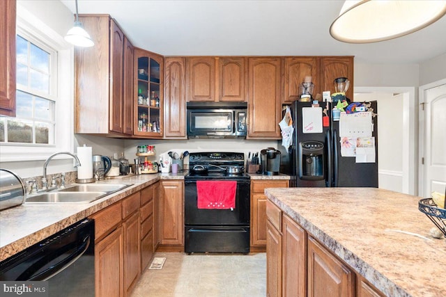 kitchen featuring decorative light fixtures, a sink, light countertops, black appliances, and glass insert cabinets