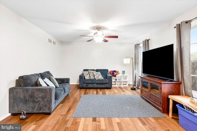 living area with ceiling fan, visible vents, baseboards, and wood finished floors