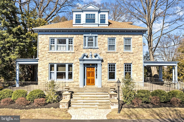 georgian-style home featuring stone siding and roof with shingles