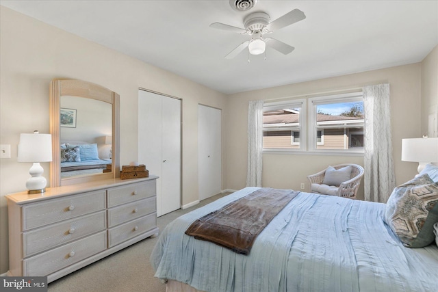 bedroom with baseboards, multiple closets, a ceiling fan, and light colored carpet