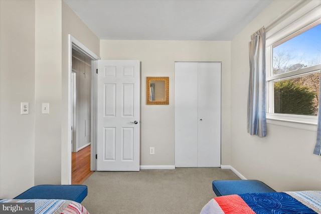 bedroom with light carpet, a closet, and baseboards