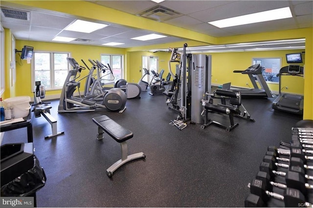 gym featuring a paneled ceiling, visible vents, and baseboards