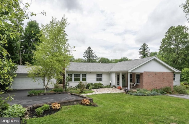 ranch-style house featuring brick siding, a front lawn, an attached garage, and aphalt driveway