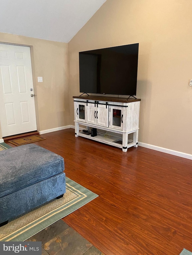 living room with vaulted ceiling, wood finished floors, and baseboards