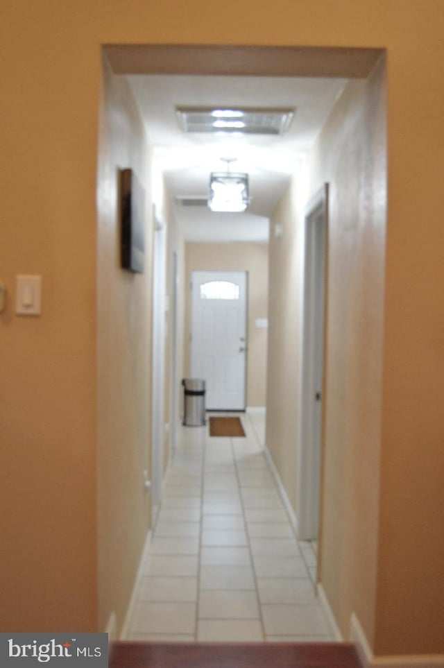 hall with visible vents, baseboards, and light tile patterned floors