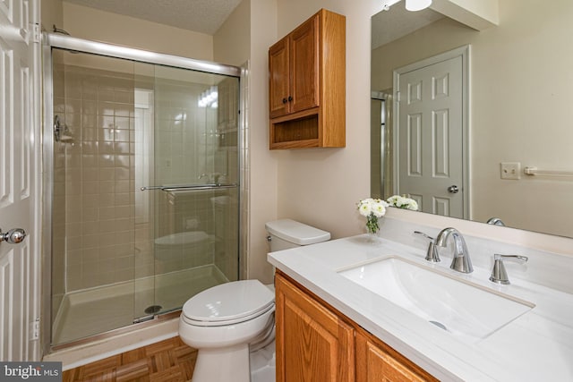 bathroom with toilet, a stall shower, a textured ceiling, and vanity