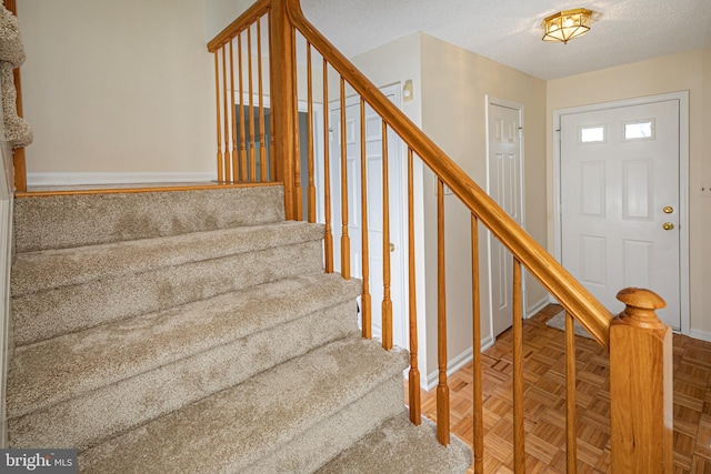 staircase with a textured ceiling and baseboards