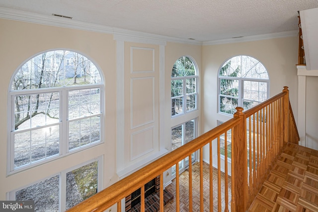 hallway with ornamental molding, visible vents, a textured ceiling, and an upstairs landing