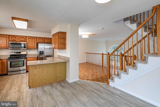 kitchen featuring stainless steel appliances, a peninsula, light countertops, brown cabinets, and open shelves