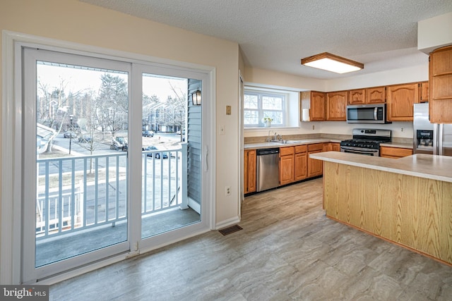 kitchen with visible vents, brown cabinets, stainless steel appliances, light countertops, and a sink