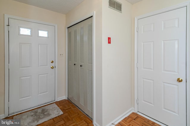 entrance foyer featuring baseboards, visible vents, and a textured ceiling