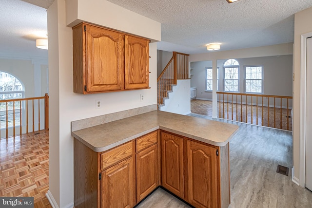 kitchen featuring brown cabinetry, light countertops, and a peninsula