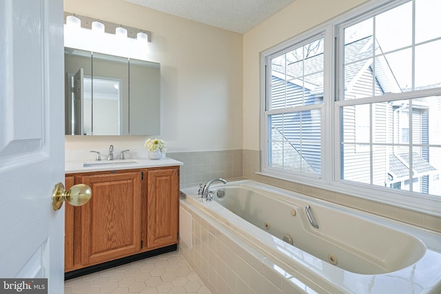 bathroom with vanity, a tub with jets, a textured ceiling, and tile patterned floors